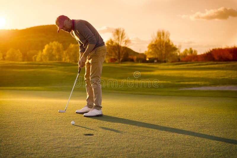 Jogador de golfe masculino que põe no por do sol fotografia de stock royalty free Jogador de golfe masculino que põe no por do sol fotografia de stock royalty free