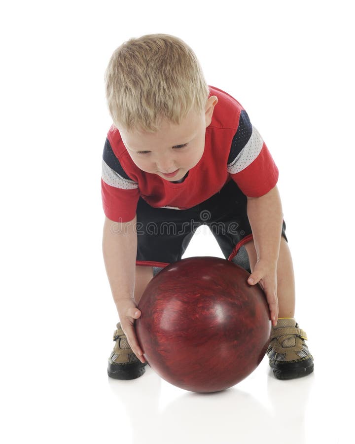 An adorable preschooler bent over while attempting to roll a heavy bowling ball. On a white background. An adorable preschooler bent over while attempting to roll a heavy bowling ball. On a white background.