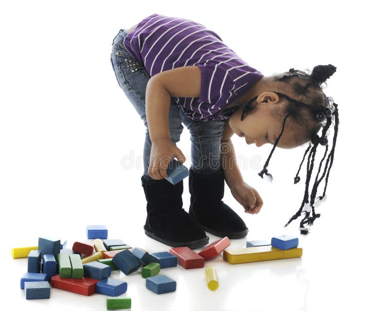 An adorable preschooler banding from the waise to play with her colorful blocks. On a white background. An adorable preschooler banding from the waise to play with her colorful blocks. On a white background.