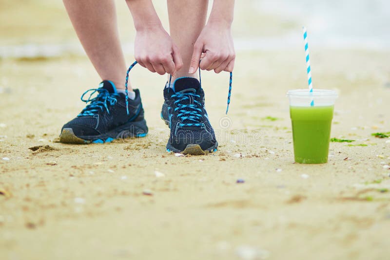 Jogger met groene plantaardige smoothie, het bindende kant van sportloopschoenen stock foto Jogger met groene plantaardige smoothie, het bindende kant van sportloopschoenen stock foto
