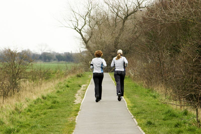 Two female joggers running along pathway