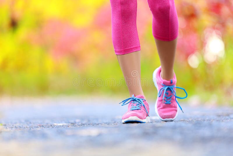 Walking and jogging woman with athletic legs and running shoes. Female walking on trail in forest in healthy lifestyle concept with close up on running shoes. Female athlete jogger training outdoors.