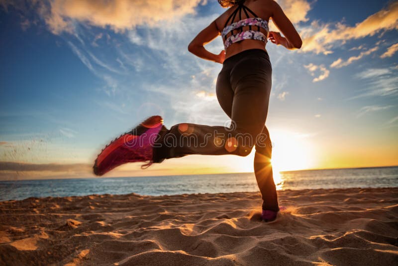 Jogginr девушки пляжа захода солнца подходящее на песке против предпосылки захода солнца стоковая фотография Jogginr девушки пляжа захода солнца подходящее на песке против предпосылки захода солнца стоковая фотография