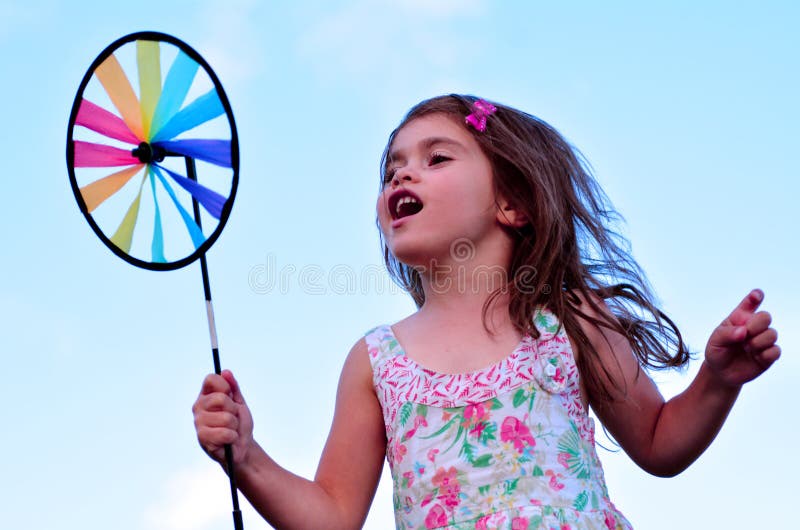 Jogo da menina com o moinho de vento do brinquedo do girândola imagens de stock royalty free Jogo da menina com o moinho de vento do brinquedo do girândola imagens de stock royalty free