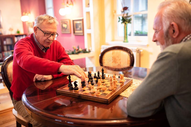 Amigos de xadrez e jogos de tabuleiro na mesa de madeira pensando em  movimento estratégico ou tático em casa grupo sênior de homens jogando e  segurando ou movendo a peça branca para