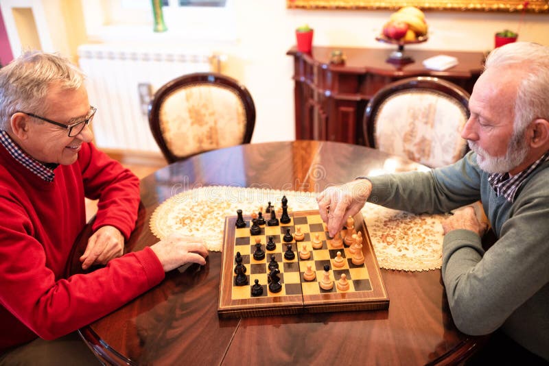 Amigos de xadrez e jogos de tabuleiro na mesa de madeira pensando em  movimento estratégico ou tático em casa grupo sênior de homens jogando e  segurando ou movendo a peça branca para