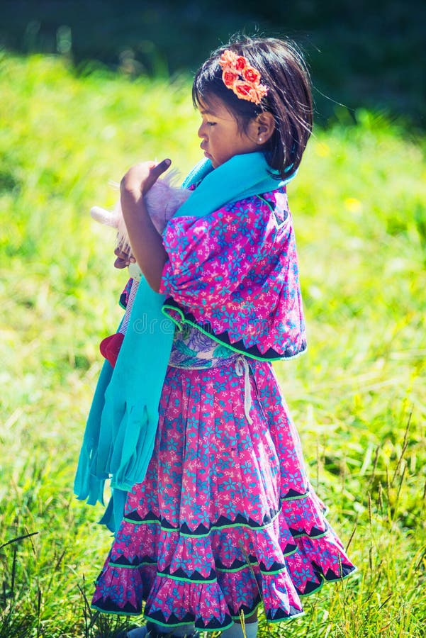 Jogo nativo nativo da menina com a boneca no vestido colorido tradicional na pastagem com bondade, México, América imagens de stock Jogo nativo nativo da menina com a boneca no vestido colorido tradicional na pastagem com bondade, México, América imagens de stock