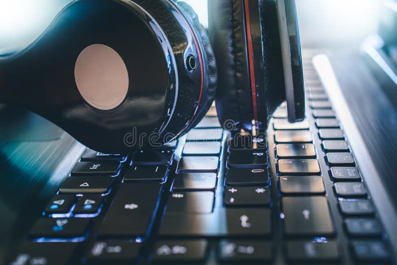 Jogo sem fio preto ou Deejay Headphone Lying On um teclado de computador com luz brilhante no fundo fotografia de stock
