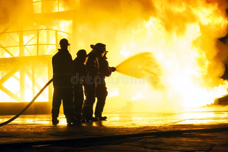 JOHANNESBURG, SÜDAFRIKA - Mai 2018 Feuerwehrmänner, die Wasser am Feuer während einer feuerbekämpfenden Schulungsübung sprühen stockfoto JOHANNESBURG, SÜDAFRIKA - Mai 2018 Feuerwehrmänner, die Wasser am Feuer während einer feuerbekämpfenden Schulungsübung sprühen stockfoto
