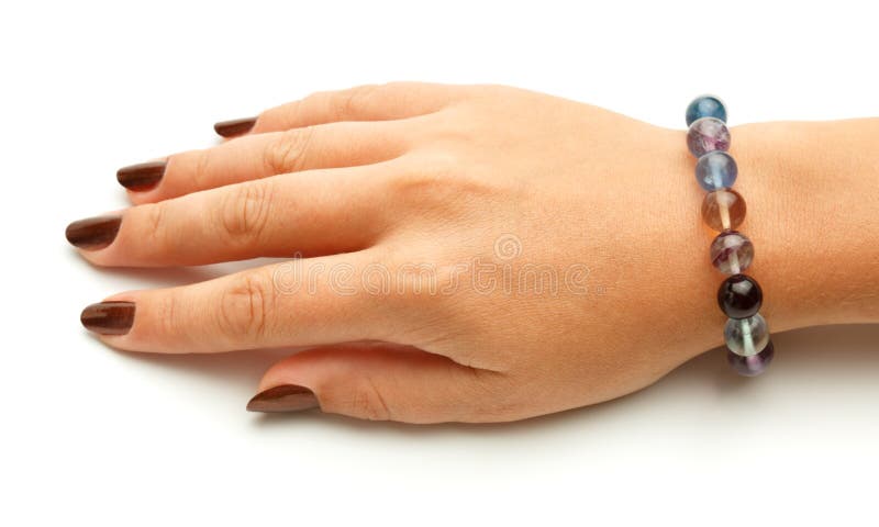 Beautiful bracelet made of colorful fluorite round beads on elegant female hand isolated on white background. Close up. Beautiful bracelet made of colorful fluorite round beads on elegant female hand isolated on white background. Close up.