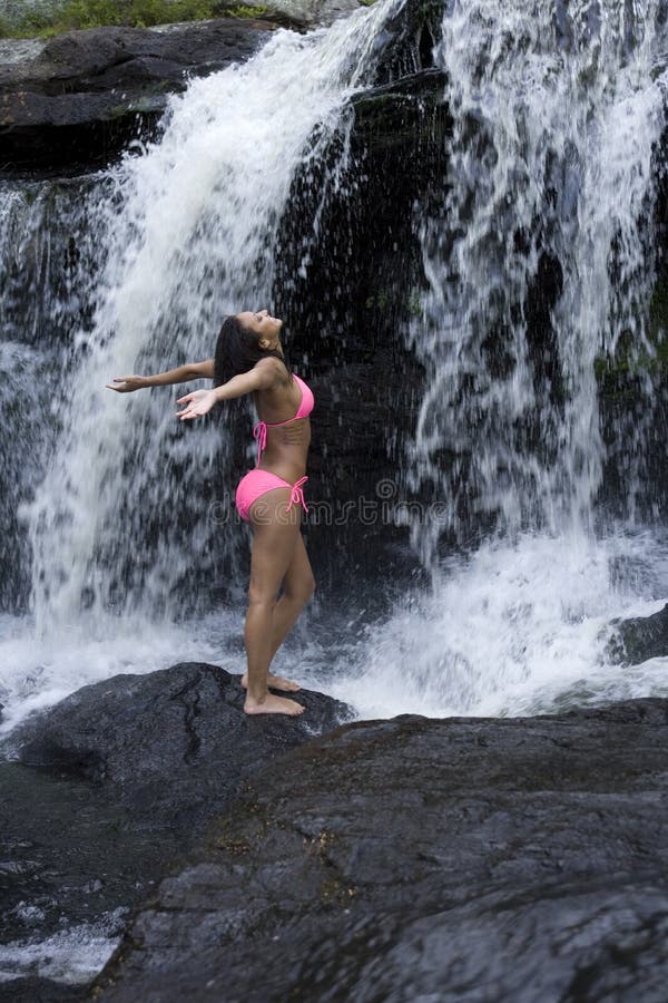 Lovely young Hispanic African American woman shows joy at being at a waterfall. Lovely young Hispanic African American woman shows joy at being at a waterfall