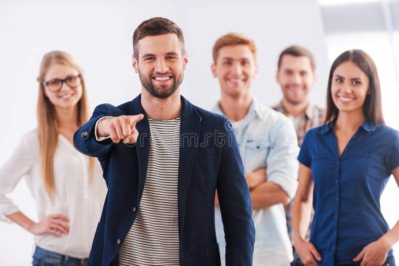 Beautiful young women showing her thumb up and smiling while group of happy young people standing on background and smiling. Beautiful young women showing her thumb up and smiling while group of happy young people standing on background and smiling