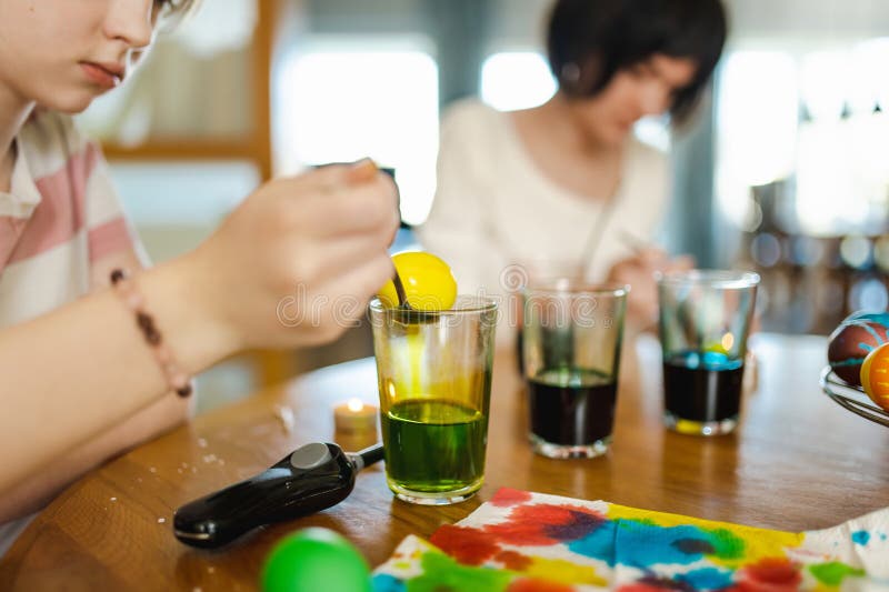 Jolie adolescente teintant les oeufs de Pâques à la maison. OEufs colorés pour la chasse de Pâques. Enfant prêt pour Pâques photographie stock