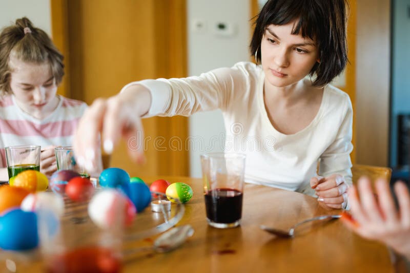 Jolie adolescente teintant les oeufs de Pâques à la maison. OEufs colorés pour la chasse de Pâques. Enfant prêt pour Pâques photos libres de droits