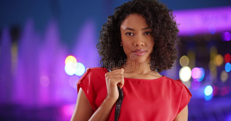 Jolie femme africaine aux cheveux bouclés souriant par une fontaine colorée la nuit banque de vidéos