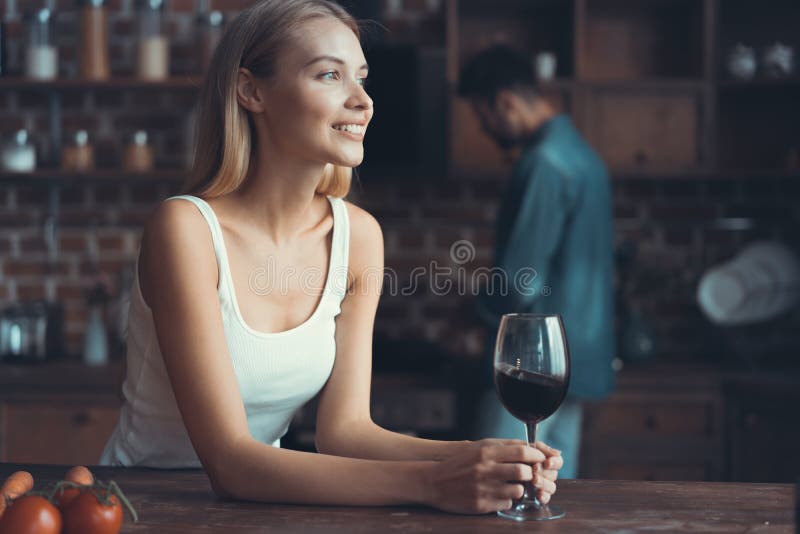 Jolie femme buvant du vin à la maison dans la cuisine image stock
