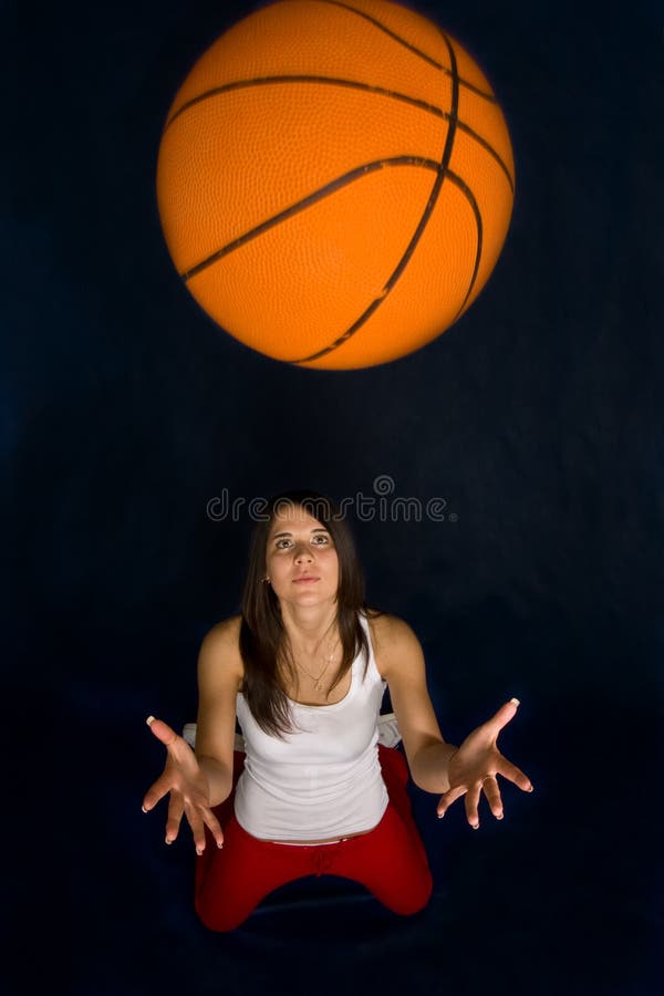 Pretty woman playing basketball against a blue background. Pretty woman playing basketball against a blue background