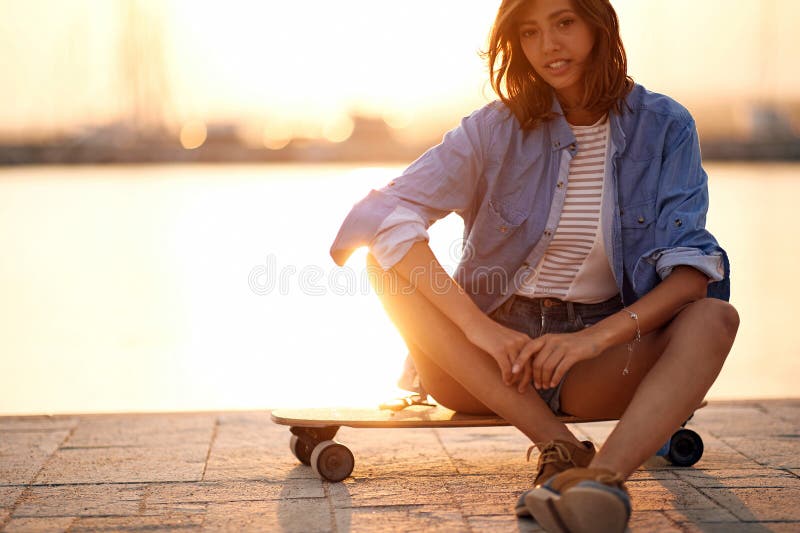 Jolie femme posant avec le skateboard photographie stock libre de droits