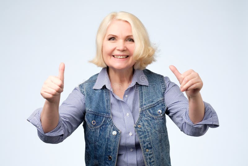 Jolie femme supérieure de sourire montrant des pouces photographie stock Jolie femme supérieure de sourire montrant des pouces photographie stock
