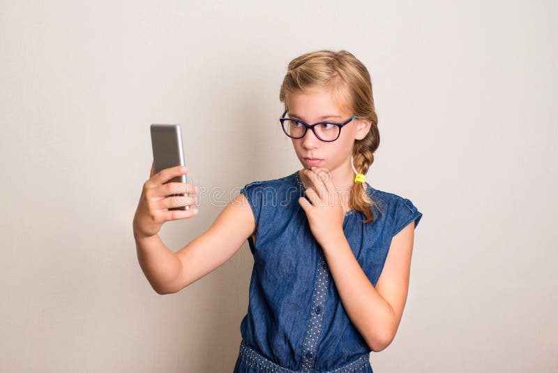 Jolie fille de l'adolescence de sourire en verres faisant la photo de selfie sur futé photo libre de droits Jolie fille de l'adolescence de sourire en verres faisant la photo de selfie sur futé photo libre de droits