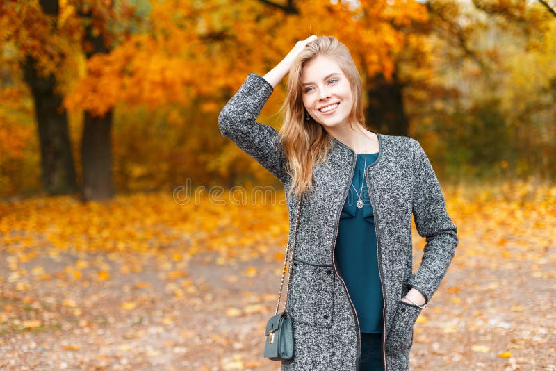 Jolie jeune belle femme élégante dans le manteau gris élégant à la mode dans le chemisier vert élégant sur un extérieur de promen image stock Jolie jeune belle femme élégante dans le manteau gris élégant à la mode dans le chemisier vert élégant sur un extérieur de promen image stock