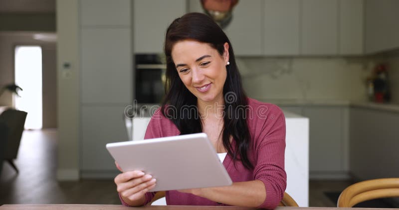 Jolie jeune femme assise dans une cuisine confortable avec tablette numérique clips vidéos