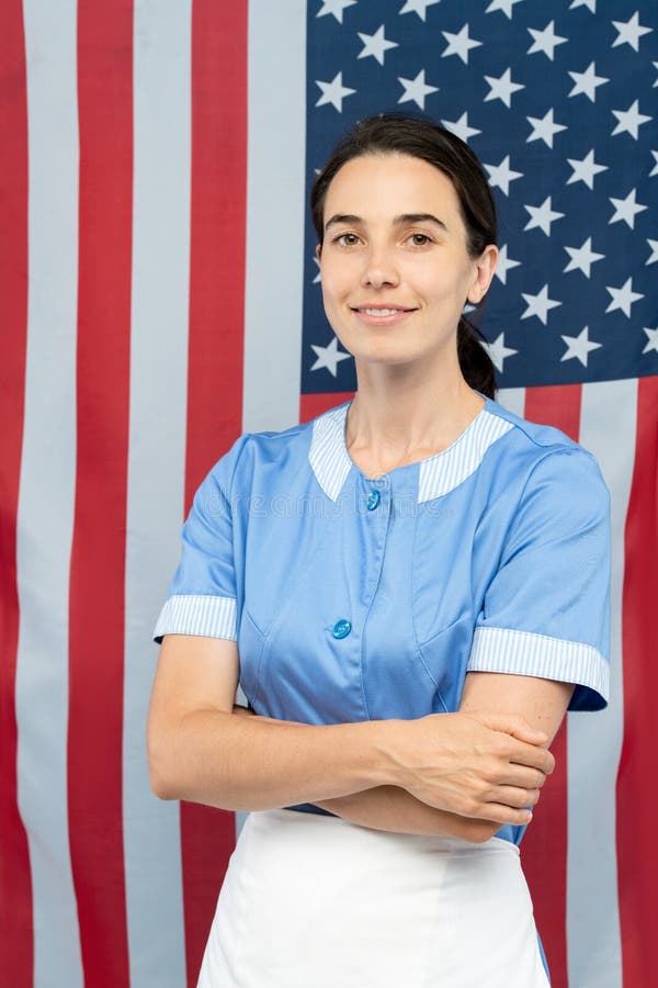 Jolie jeune femme de chambre gay dans les bras de franchissement uniformes bleus par la poitrine image libre de droits