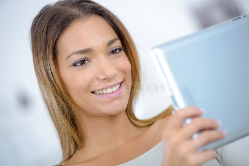 Jolie jeune femme détendant avec la tablette photo stock Jolie jeune femme détendant avec la tablette photo stock
