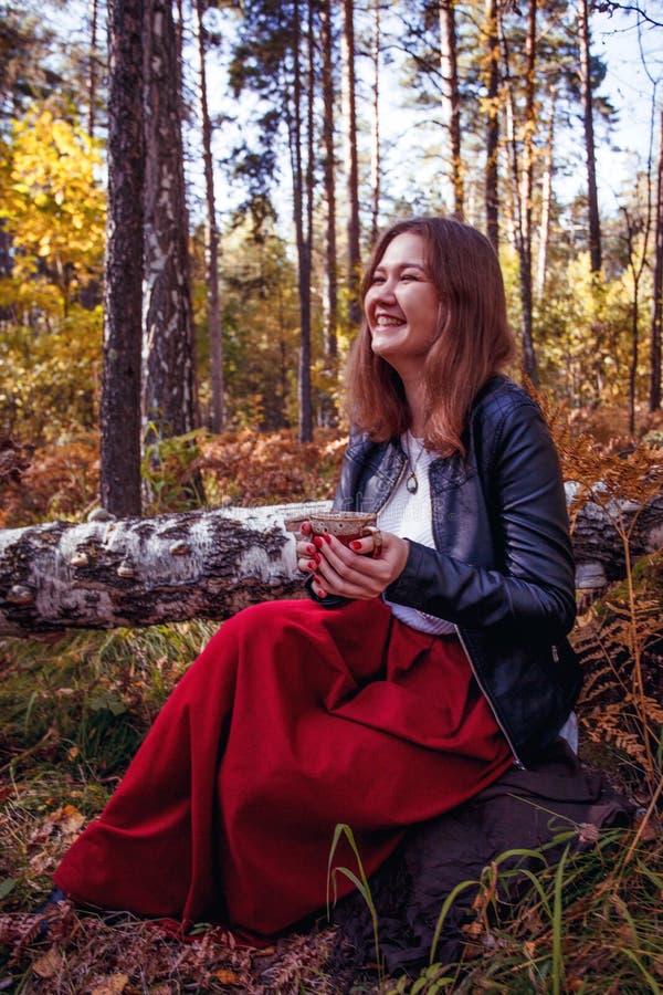 Jolie jeune femme heureuse avec une tasse de thé pose dans le parc. Une fille joyeuse aime marcher dehors. Grand week-end. Saison photographie stock libre de droits Jolie jeune femme heureuse avec une tasse de thé pose dans le parc. Une fille joyeuse aime marcher dehors. Grand week-end. Saison photographie stock libre de droits