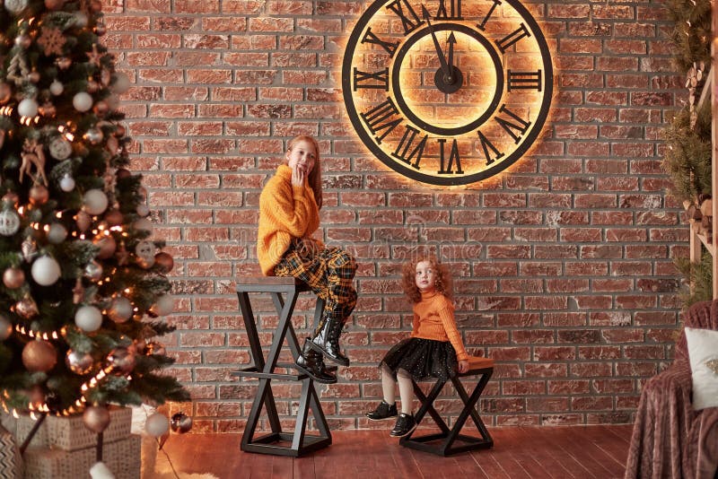Jolies soeurs s'asseyant dans un salon élégant le réveillon de Noël photos stock Jolies soeurs s'asseyant dans un salon élégant le réveillon de Noël photos stock