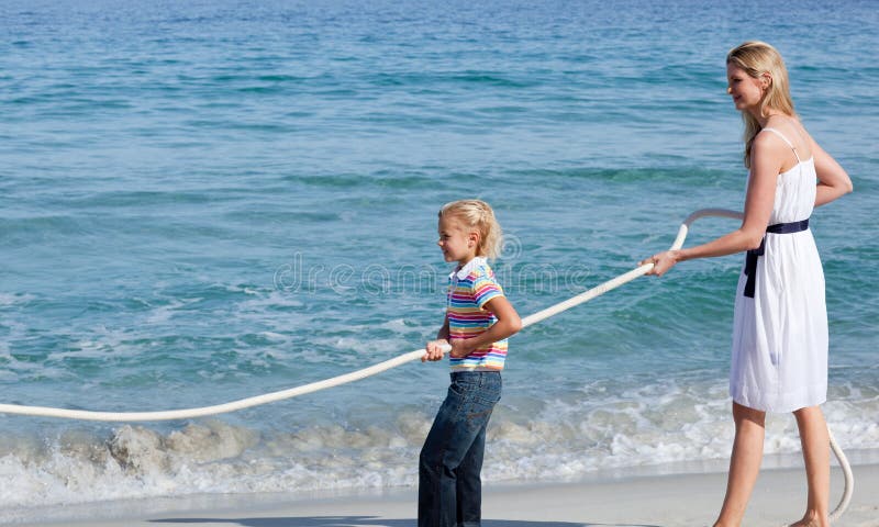 Jolly family playing tug of war at the beach