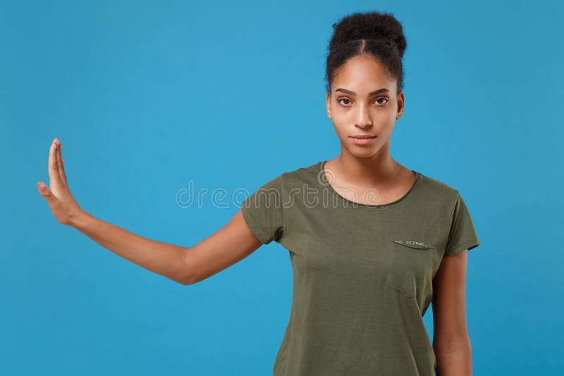 Young african american woman girl in casual t-shirt posing isolated on bright blue wall background studio portrait. People lifestyle concept. Mock up copy space. Showing stop gesture with palm aside. Young african american woman girl in casual t-shirt posing isolated on bright blue wall background studio portrait. People lifestyle concept. Mock up copy space. Showing stop gesture with palm aside