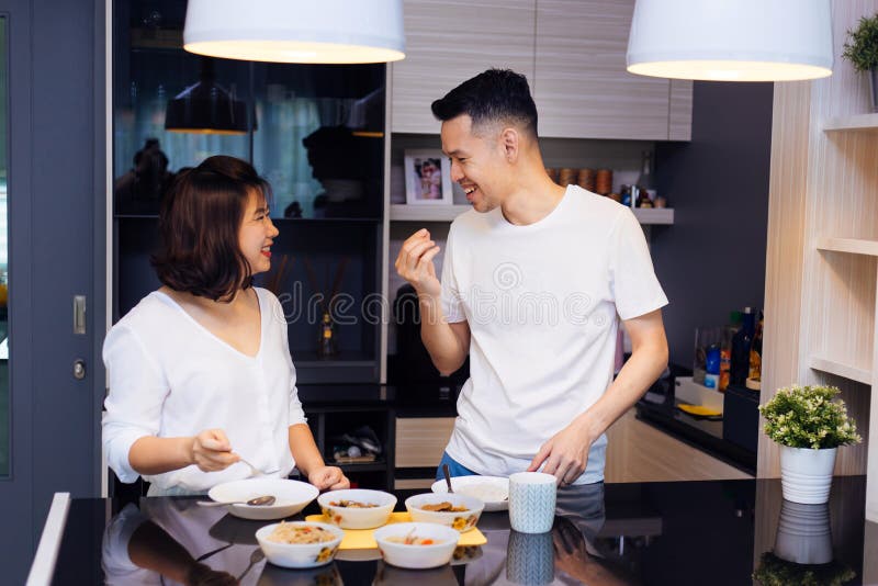 Jong Aziatisch paar die samen koken terwijl de vrouw voedsel aan de mens bij de keuken voedt Gelukkig paar en verhoudingsconcept royalty-vrije stock afbeeldingen Jong Aziatisch paar die samen koken terwijl de vrouw voedsel aan de mens bij de keuken voedt Gelukkig paar en verhoudingsconcept royalty-vrije stock afbeeldingen