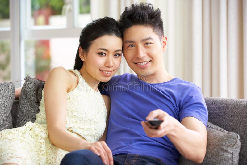 Jong Chinees Paar dat op TV op Bank thuis let royalty-vrije stock foto Jong Chinees Paar dat op TV op Bank thuis let royalty-vrije stock foto