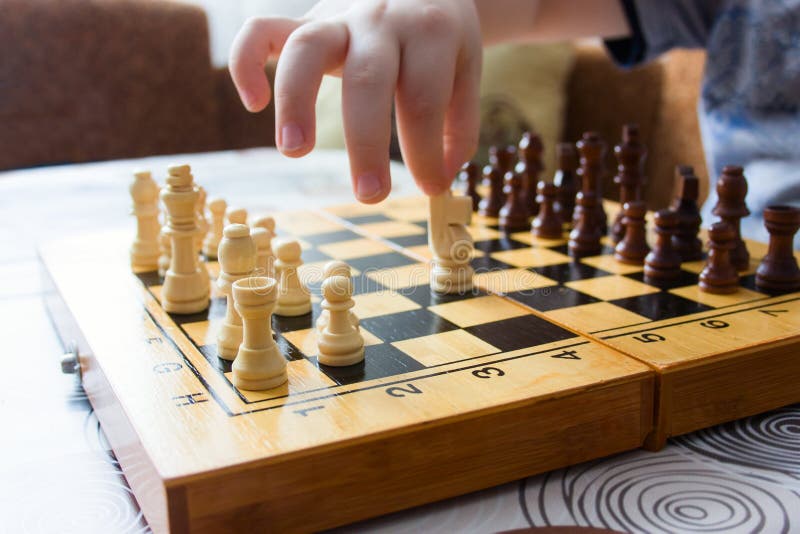 Jong geitje het spelen het schaak thuis, close-up van de hand van een kind beweegt een schaakstuk