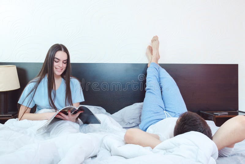 Jong gelukkig glimlachend paar in het vroege tijdschrift van de ochtendlezing stock afbeeldingen Jong gelukkig glimlachend paar in het vroege tijdschrift van de ochtendlezing stock afbeeldingen