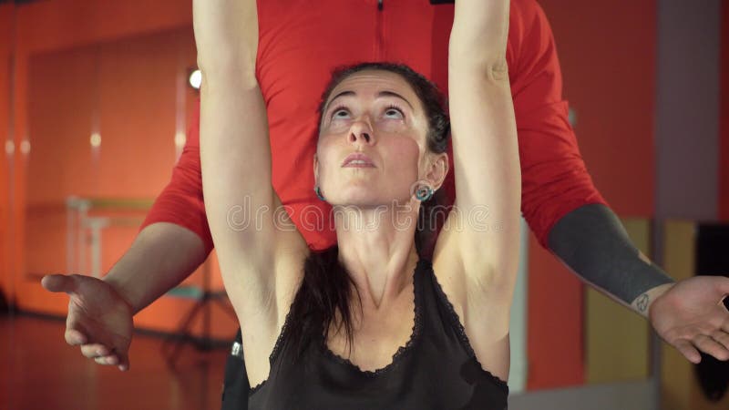 Jong gezond sportief actief vormmeisje met een knappe nuttige persoonlijke trainer naast haar in de gymnastiek