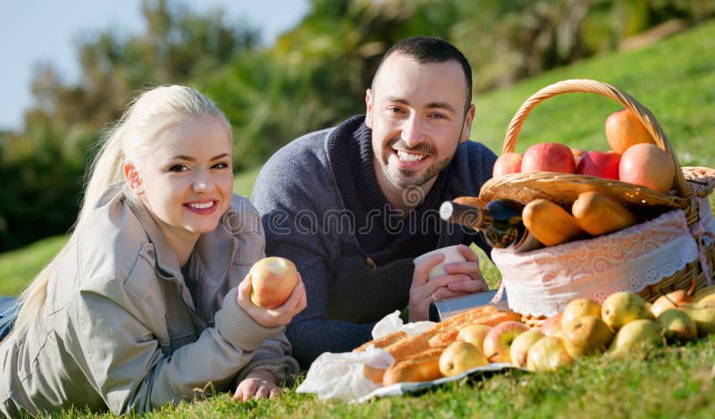 Jong glimlachend paar die zoals hebbend picknick babbelen royalty-vrije stock foto's Jong glimlachend paar die zoals hebbend picknick babbelen royalty-vrije stock foto's
