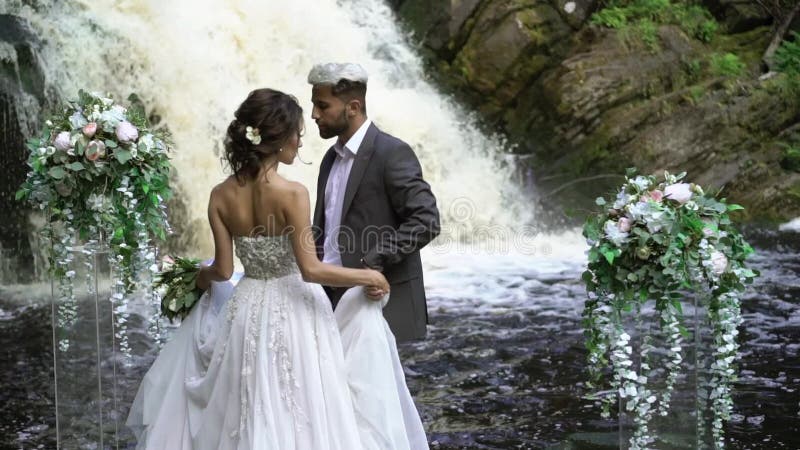 Jong huwelijkspaar die aan ceremonie dichtbij waterval lopen