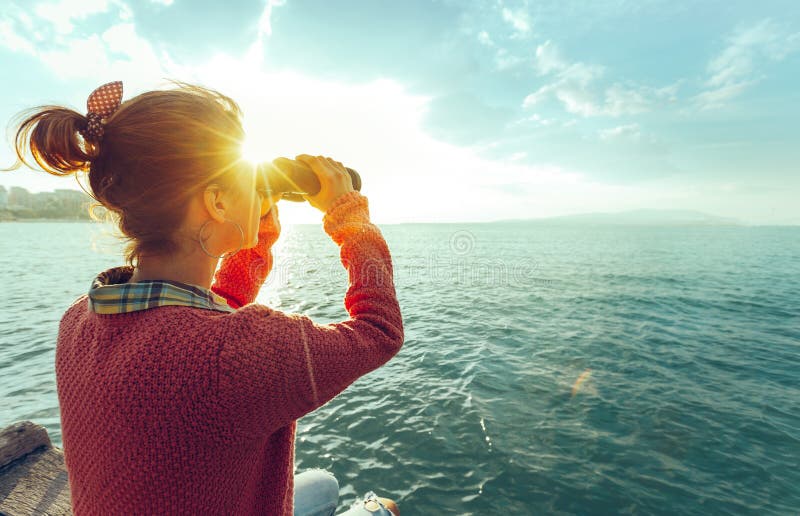 Jong Meisje die door Verrekijkers het Overzees op Helder Sunny Day, Achtermening bekijken De Reisconcept van de zwerflustreis
