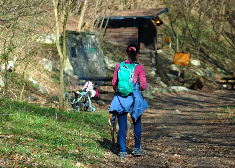 Jong meisje die in een bos met een kinderwagen op de achtergrond wandelen royalty-vrije stock foto's Jong meisje die in een bos met een kinderwagen op de achtergrond wandelen royalty-vrije stock foto's