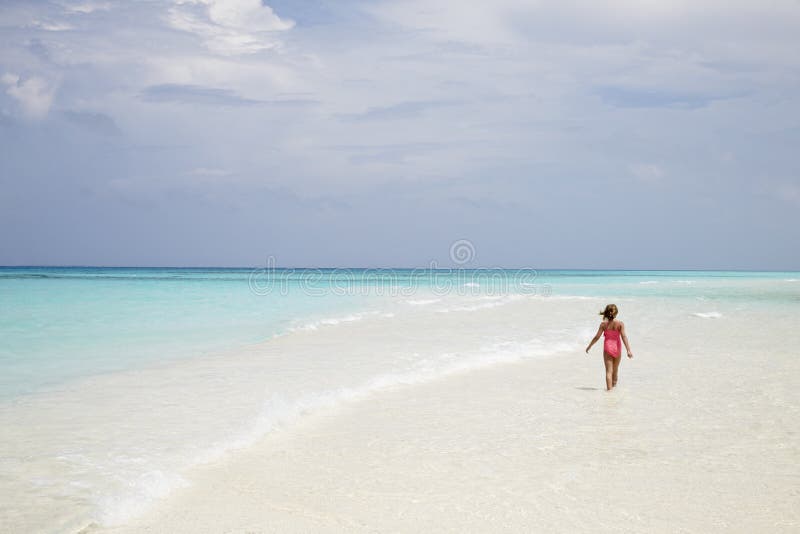 Jong meisje die op een leeg wit zandstrand lopen, achtermening royalty-vrije stock foto's Jong meisje die op een leeg wit zandstrand lopen, achtermening royalty-vrije stock foto's