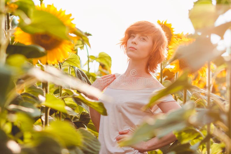 Jong meisje die van aard op het gebied van zonnebloemen genieten bij zonsondergang, portret van het mooie redheaded vrouwenmeisje royalty-vrije stock afbeelding Jong meisje die van aard op het gebied van zonnebloemen genieten bij zonsondergang, portret van het mooie redheaded vrouwenmeisje royalty-vrije stock afbeelding