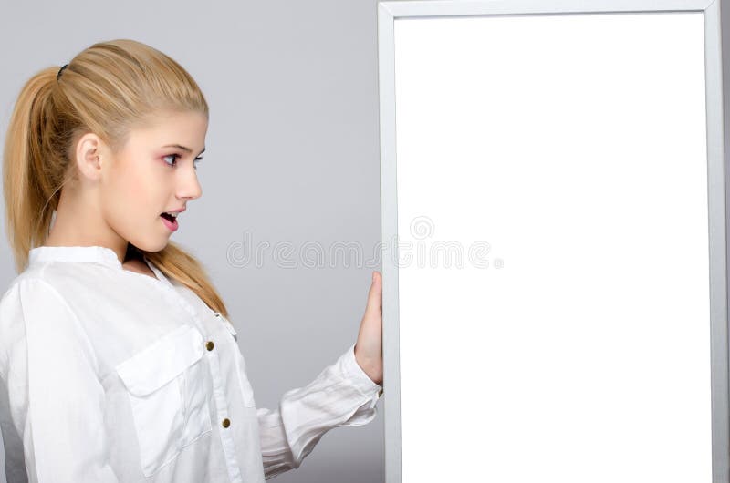 Jong meisje die verraste status dichtbij een witte raad kijken. stock foto's Jong meisje die verraste status dichtbij een witte raad kijken. stock foto's