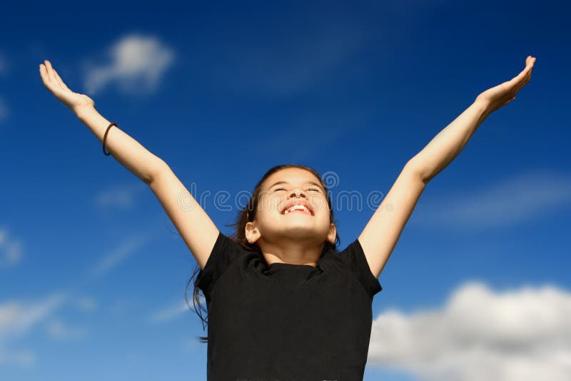 Young girl with both arms wide open, facing the bright sunshine against deep blue sky in the background, celebrating beauty of nature. Young girl with both arms wide open, facing the bright sunshine against deep blue sky in the background, celebrating beauty of nature.