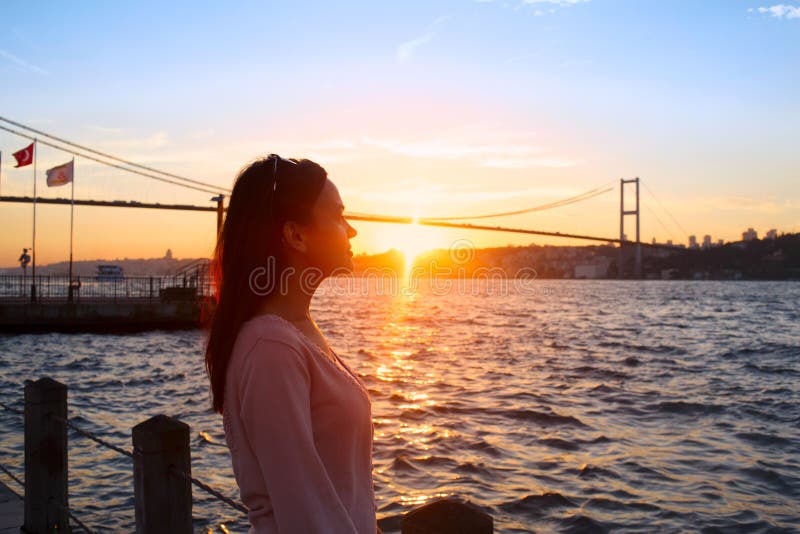 Jong meisje op achtergrond van de brug en de zonsondergang van Bosphorus stock fotografie Jong meisje op achtergrond van de brug en de zonsondergang van Bosphorus stock fotografie
