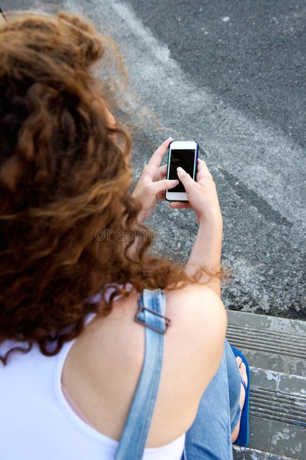 Jong meisje van het achter holding cellphone en texting royalty-vrije stock foto Jong meisje van het achter holding cellphone en texting royalty-vrije stock foto