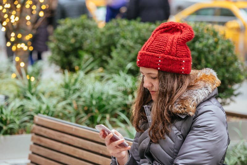 Jong mooi meisje die haar Mobiele Telefoon in de straat, lichte Achtergrond met behulp van royalty-vrije stock afbeelding Jong mooi meisje die haar Mobiele Telefoon in de straat, lichte Achtergrond met behulp van royalty-vrije stock afbeelding