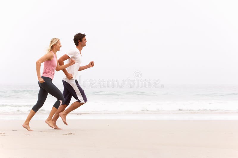 Jong Paar dat langs het Strand van de Winter loopt royalty-vrije stock afbeelding Jong Paar dat langs het Strand van de Winter loopt royalty-vrije stock afbeelding