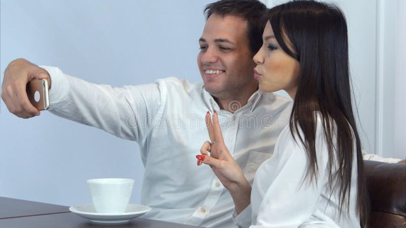 Jong paar die grappige selfies op de telefoon in een koffie nemen royalty-vrije stock afbeelding Jong paar die grappige selfies op de telefoon in een koffie nemen royalty-vrije stock afbeelding